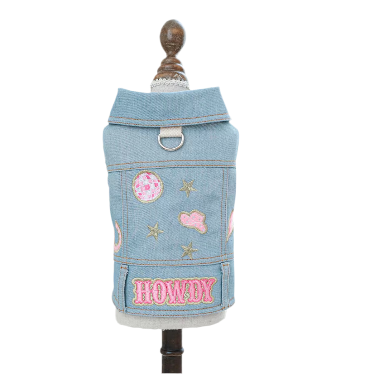 A blue denim jacket for pets with pink and white decorative patches and the text 'HOWDY' on the back.